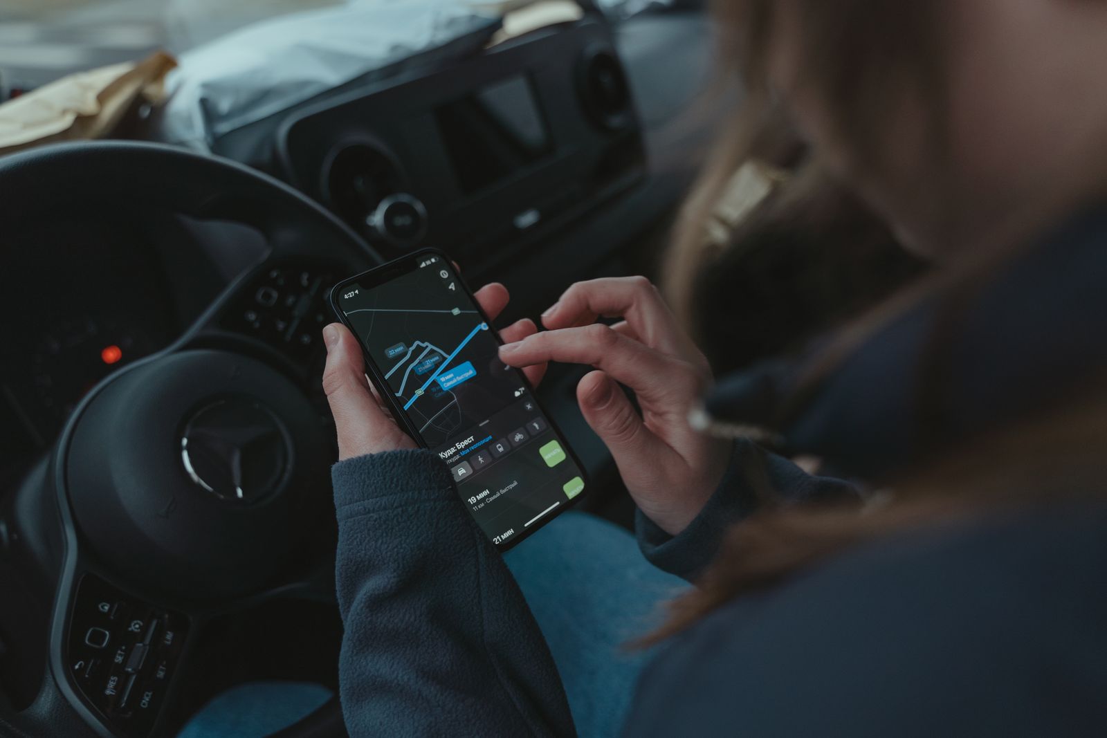 Person using GPS navigation on a smartphone inside a car