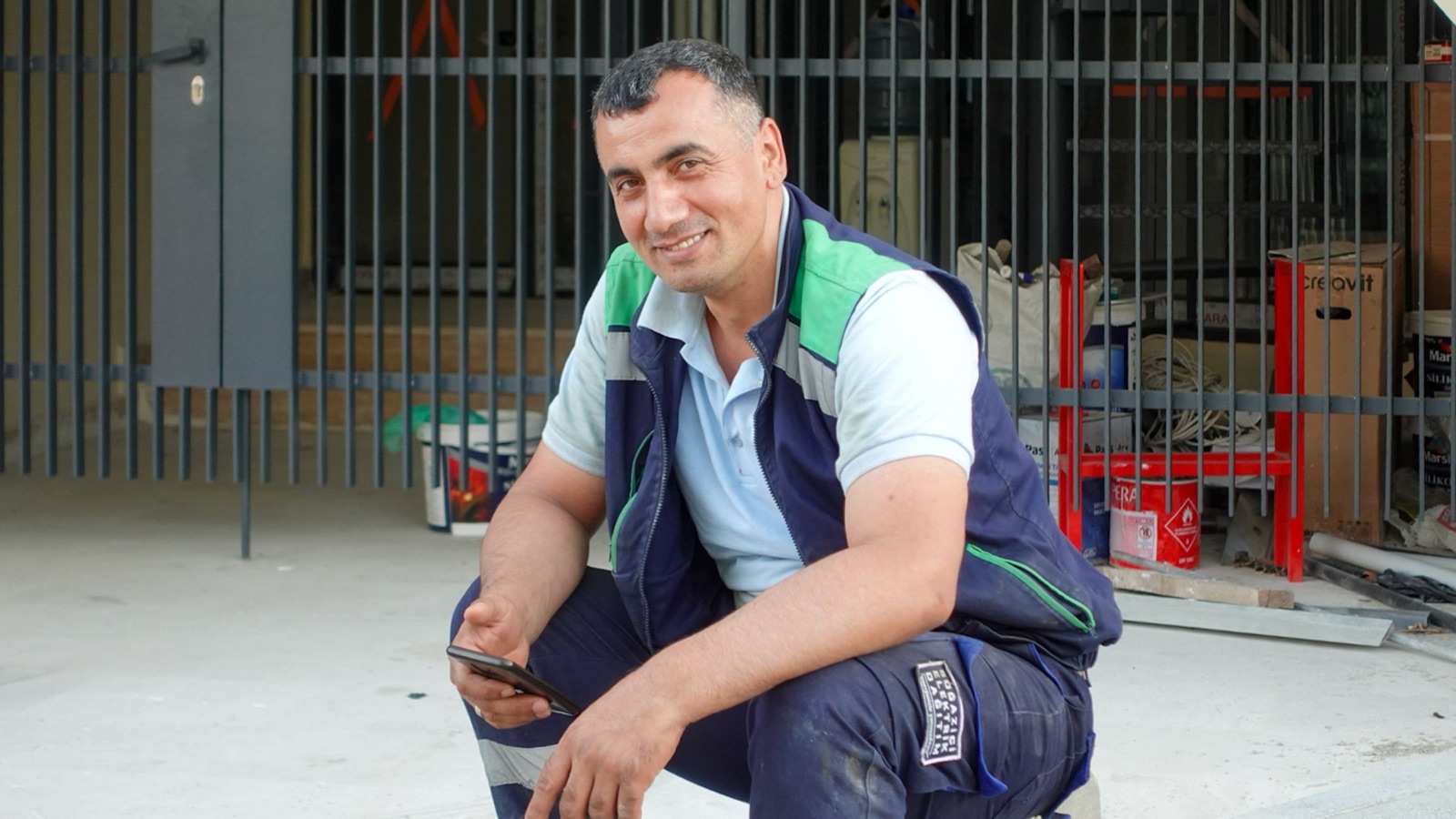 Tradesperson holding a smartphone outside a workshop