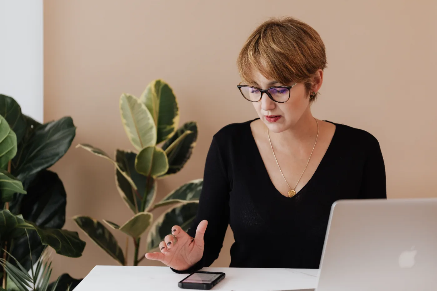 Business owner reviewing a phone beside a laptop