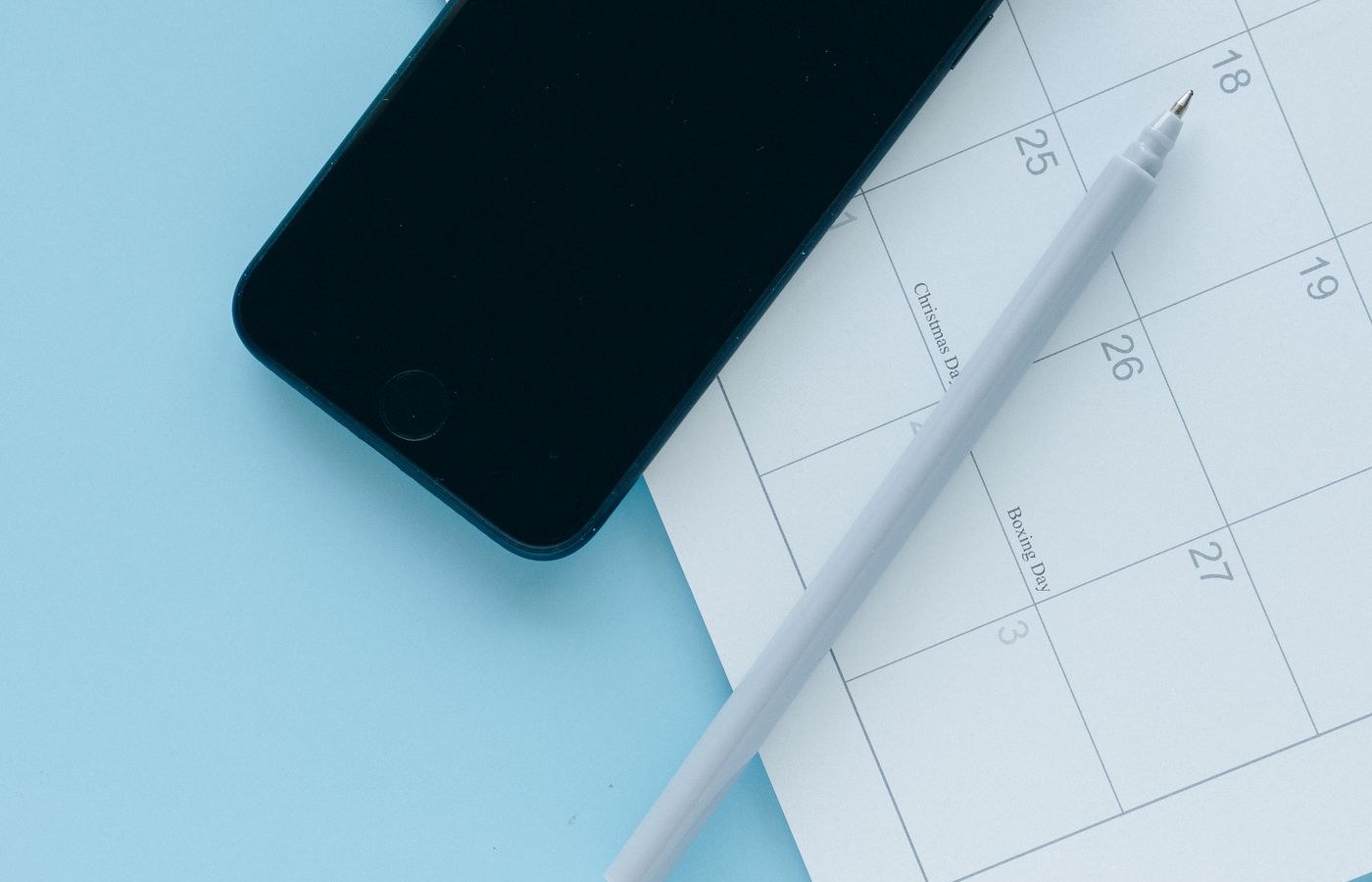Smartphone and pen on a calendar page for appointment reminder planning