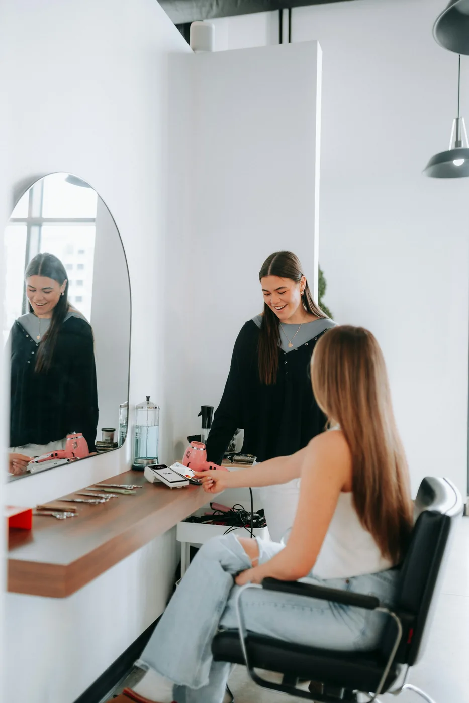 Hair stylist speaking with a seated client at a salon workstation