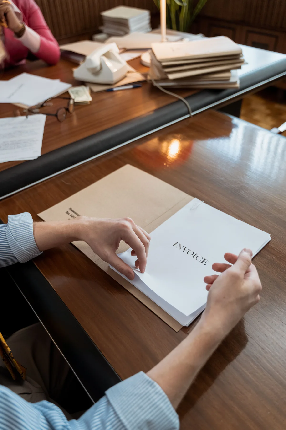 A person checking printed invoice documents at a desk