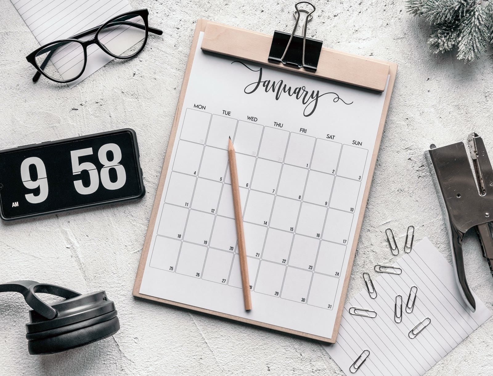 Monthly calendar and clock arranged on a desk