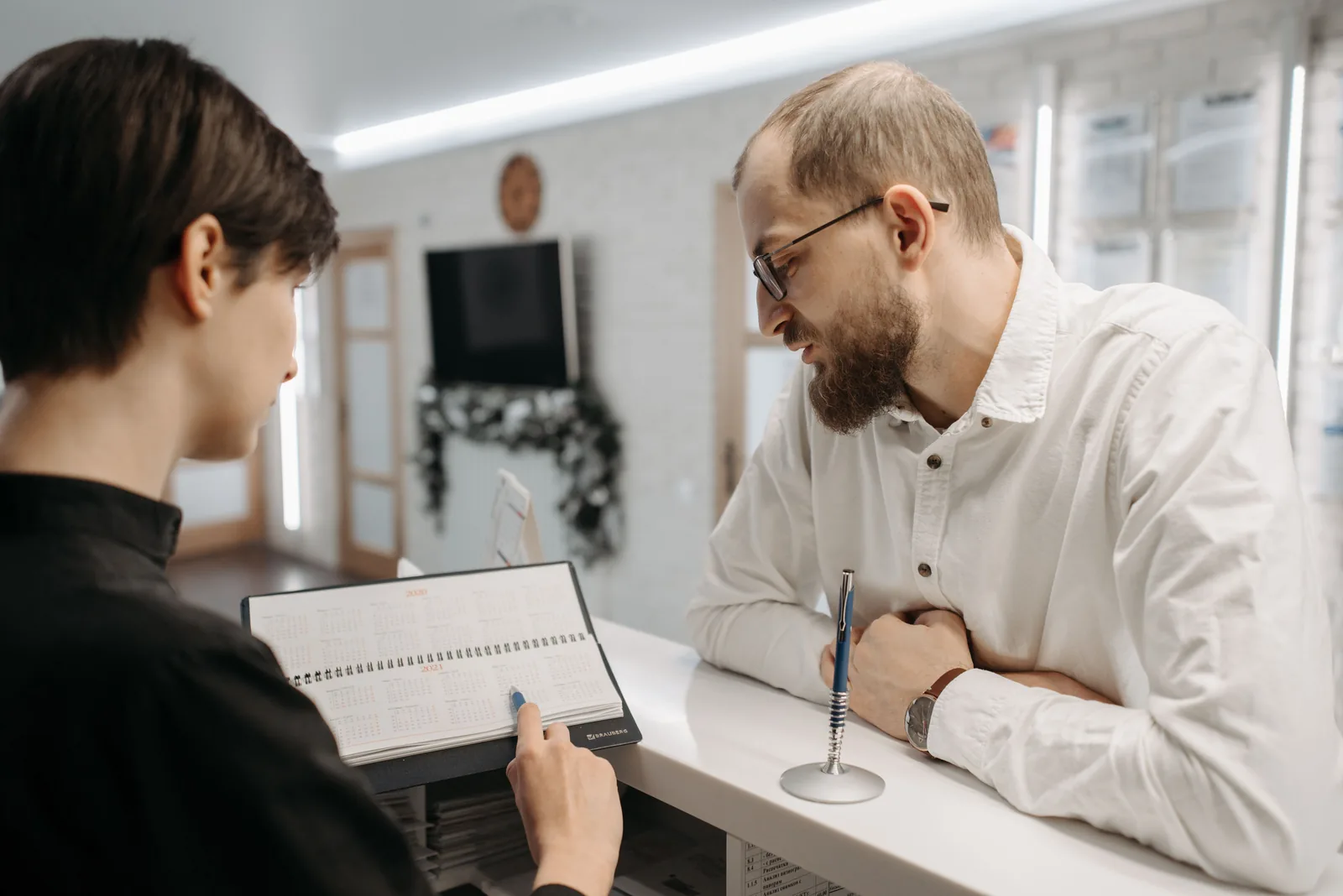A receptionist showing an appointment calendar to a customer