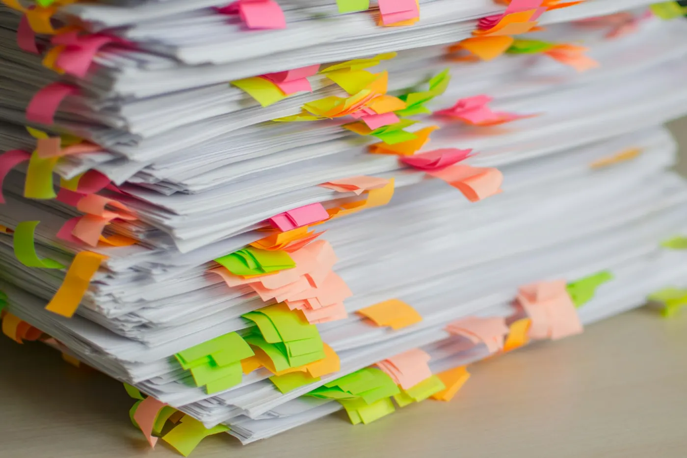 A stack of paperwork marked with colourful sticky notes