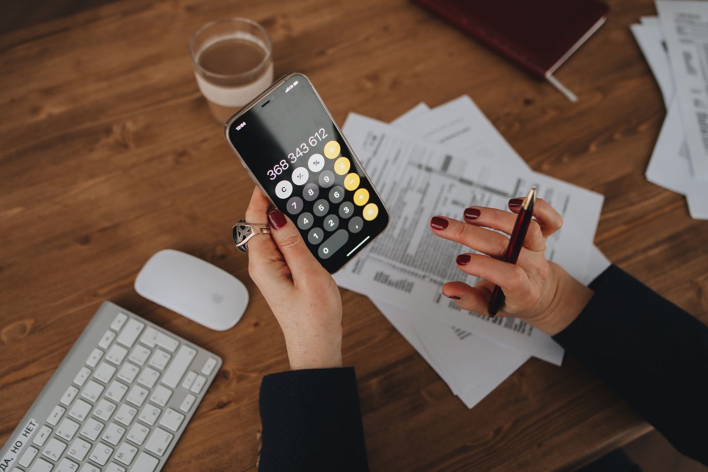 Person checking figures on a smartphone beside business documents