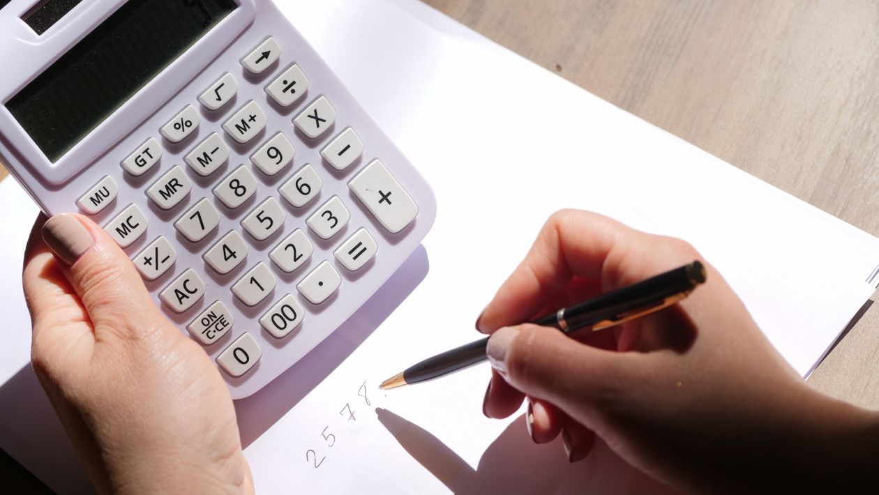 Hands using a calculator and pen to work through business figures on paper