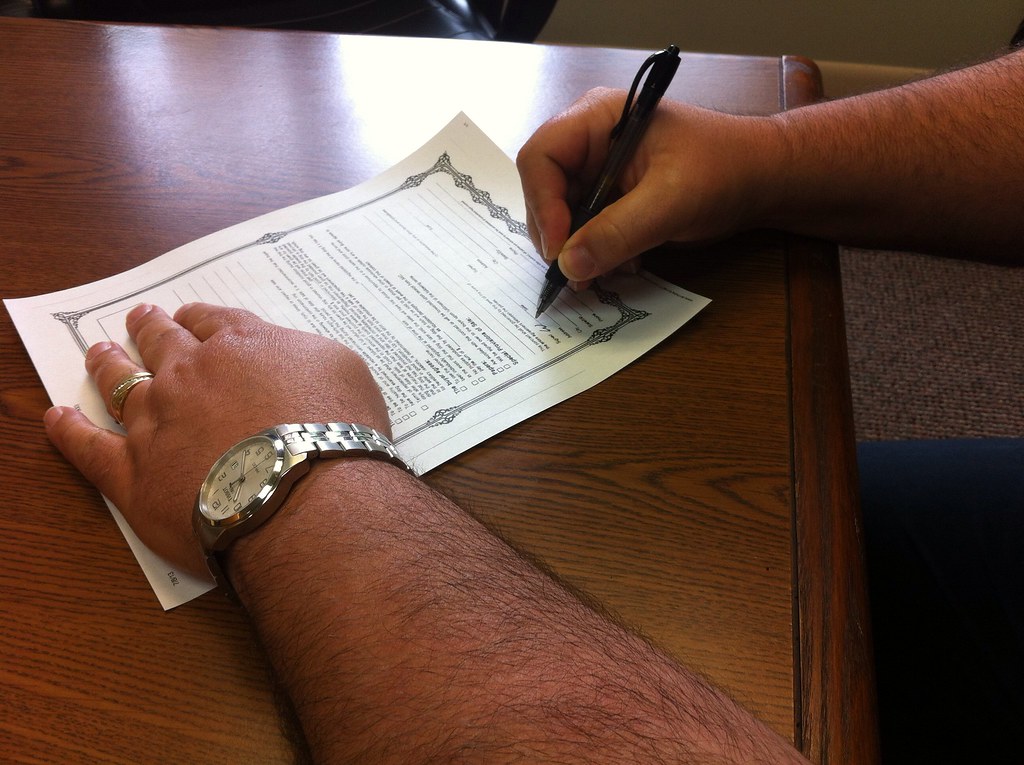 Person signing paperwork on a desk