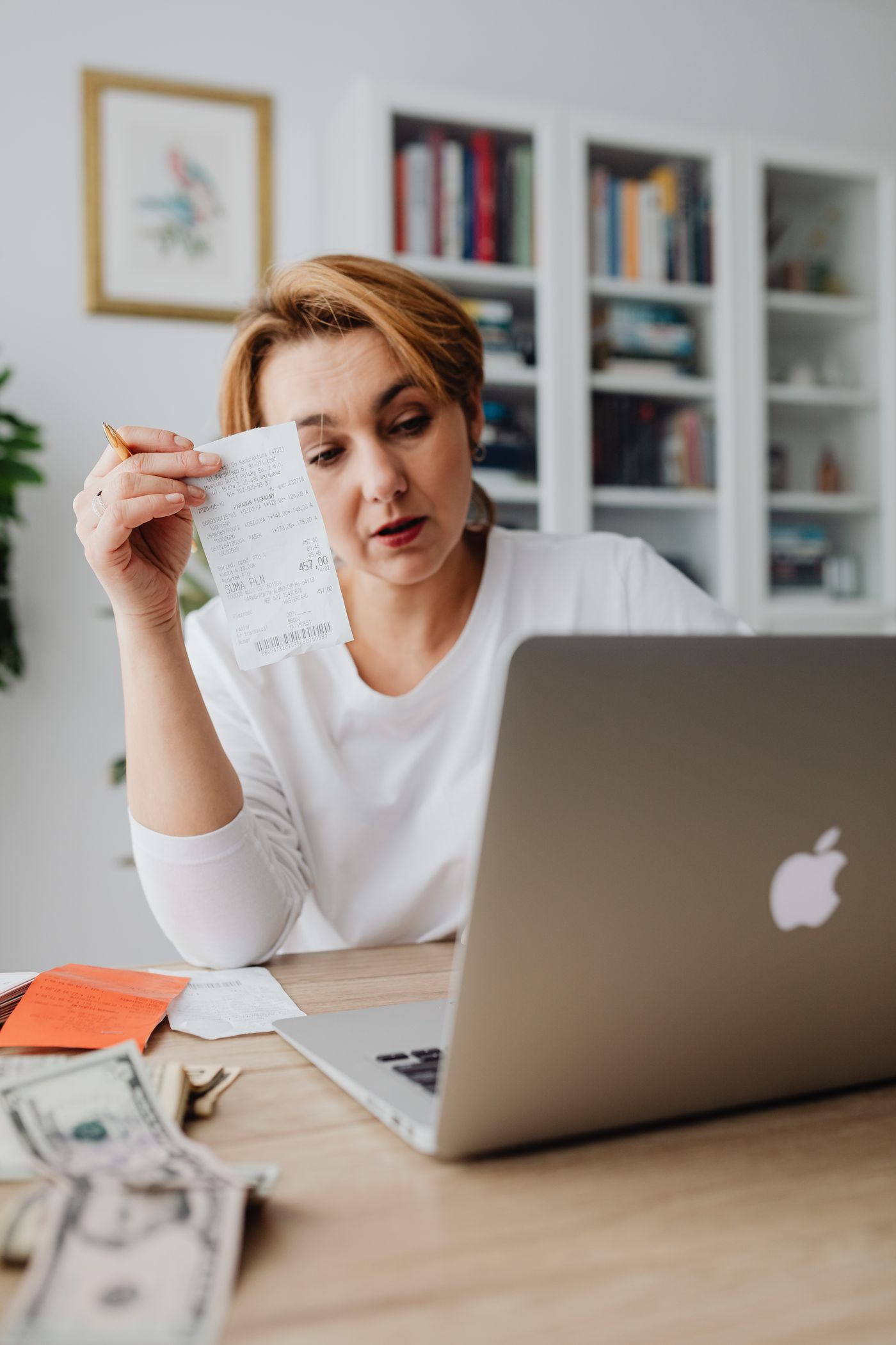Small business owner checking receipts, card takings, and invoice records at a laptop