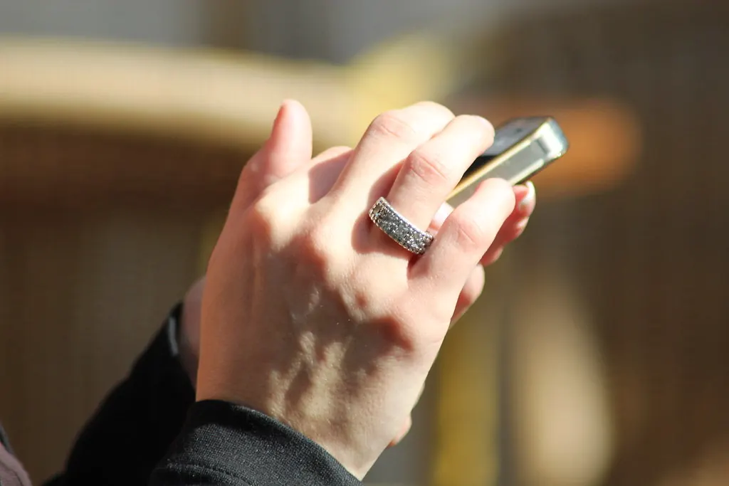 Person checking messages on a smartphone while waiting outdoors