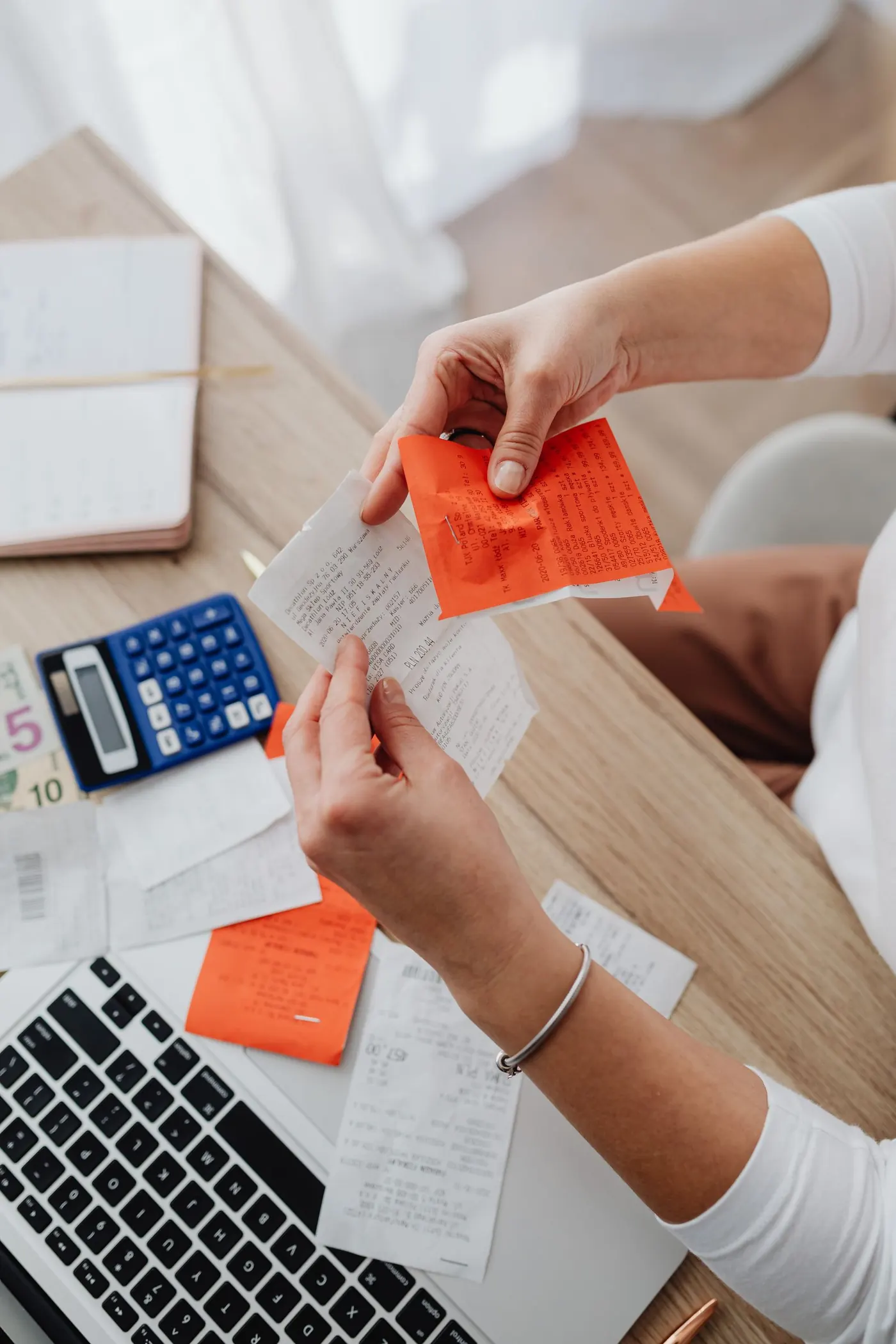 Hands organising receipts and notes with a calculator