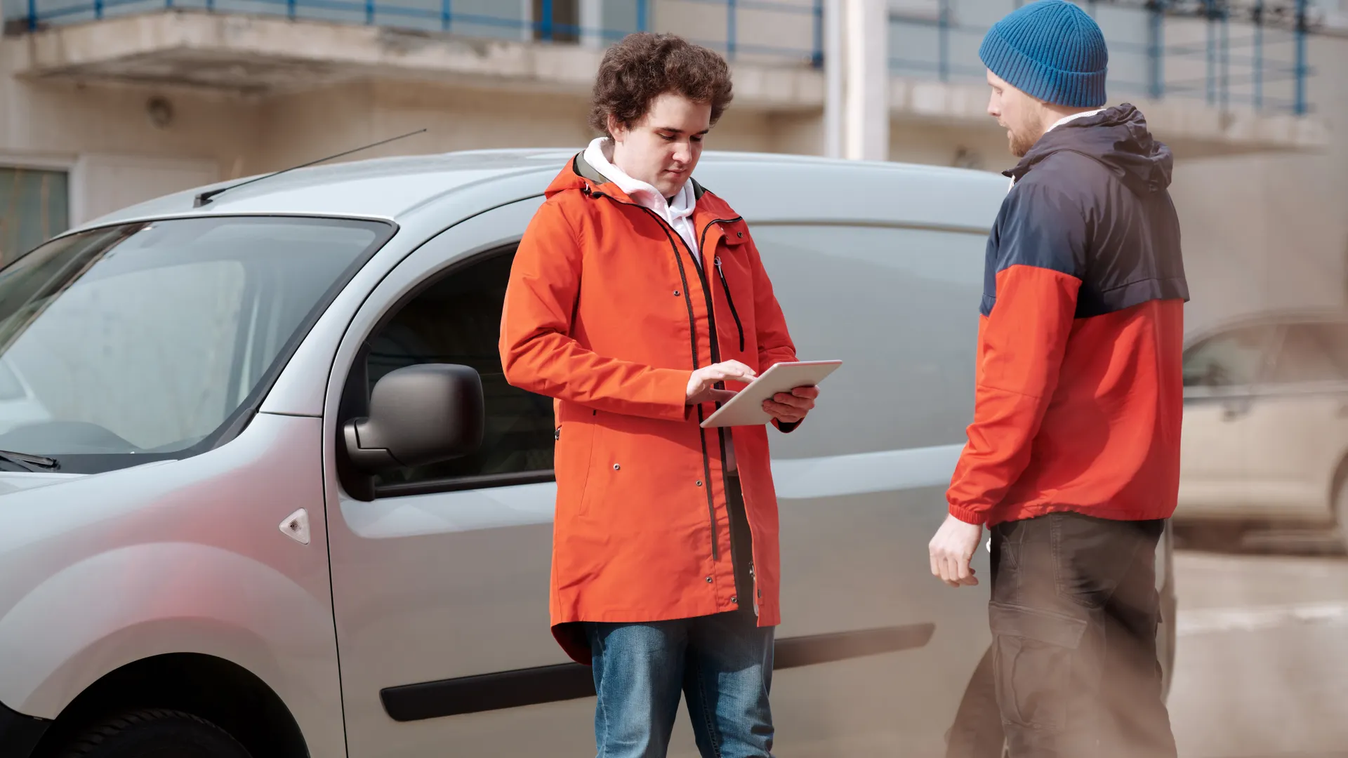 Mobile workers checking a digital record on a tablet beside a van