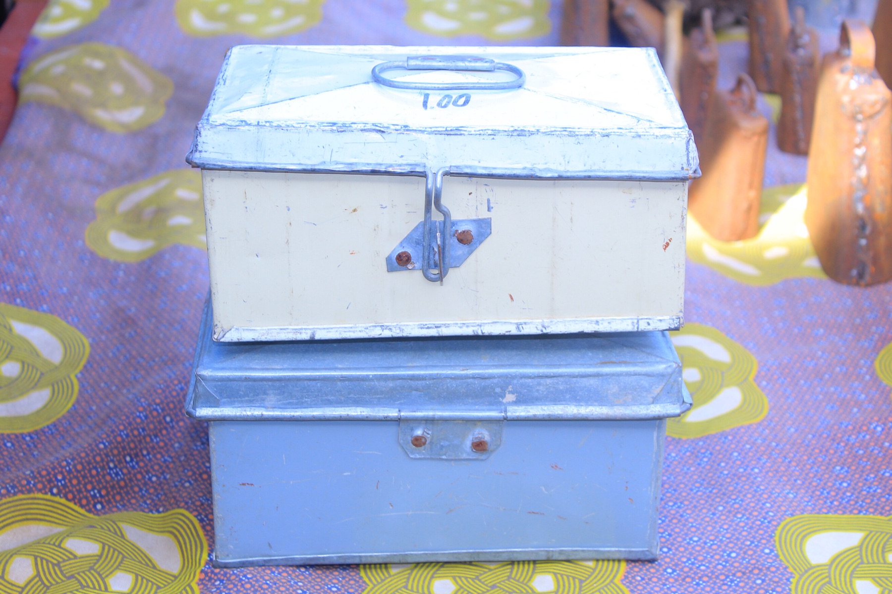 Two lockable metal petty cash boxes stacked on a patterned surface