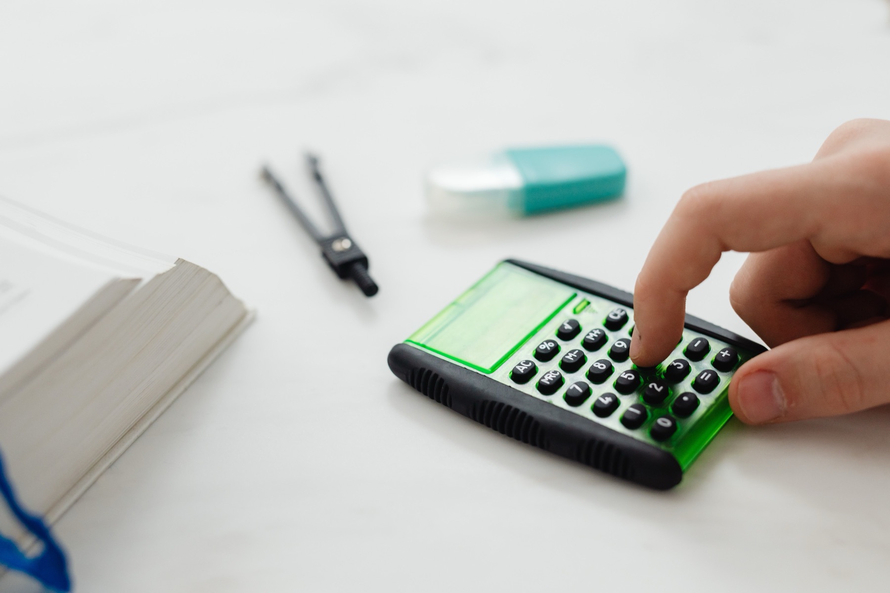 A person pressing keys on a calculator beside an open paper record