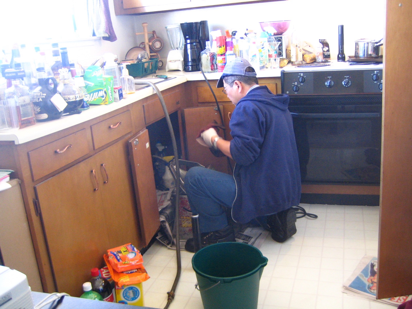 Plumber working in a kitchen with tools and drainage equipment