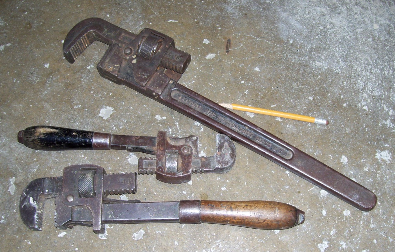 Pipe wrenches and plumbing tools on a workshop floor