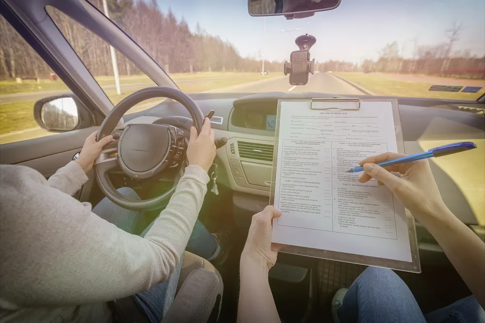 Examiner filling out a form beside a car during a practical appointment