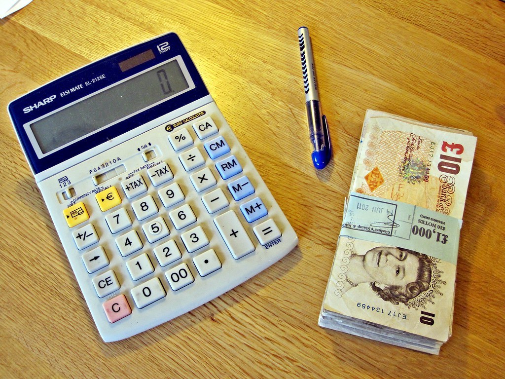 Calculator, pen and UK notes on a desk