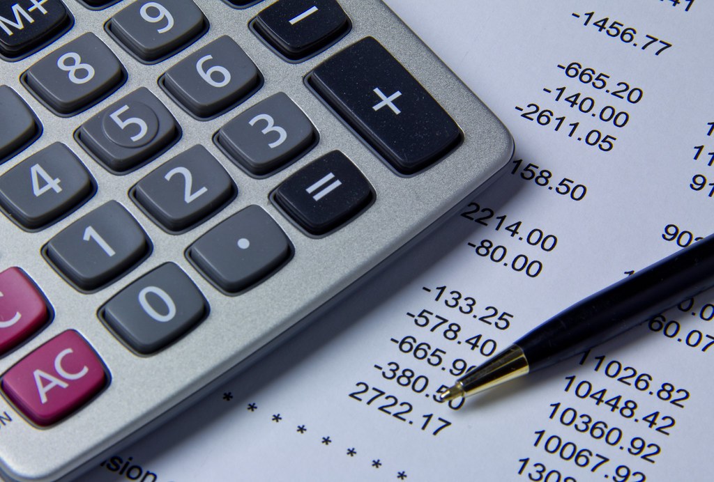 Calculator beside printed financial figures and a pen