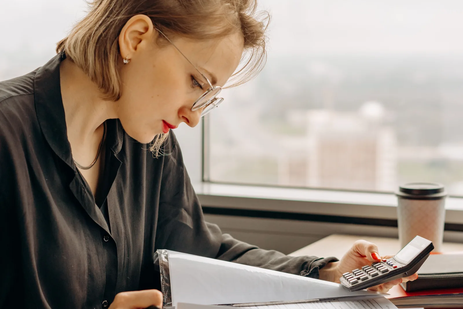 Woman reviewing written figures with a calculator