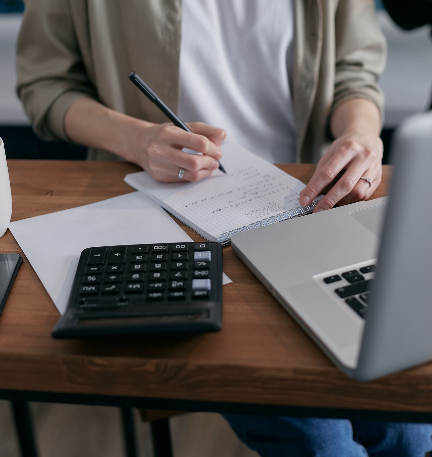 Sole trader reviewing figures beside a calculator and laptop