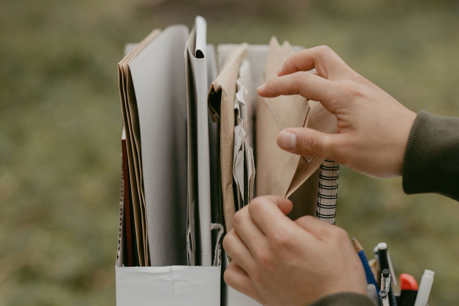 Hands placing paper folders into a filing box