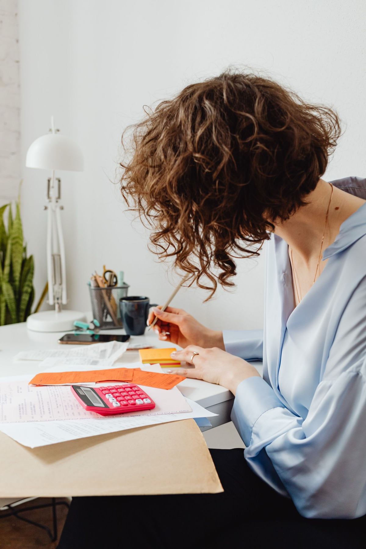 Woman sorting receipts and calculations with a calculator at a desk