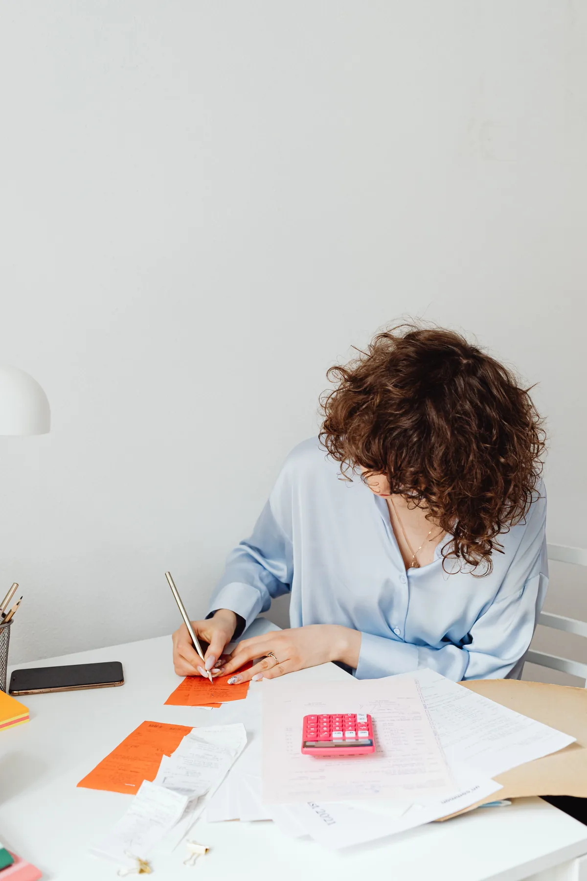 A person sorting business receipts beside a calculator and working papers
