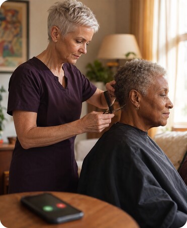 Mobile hairdresser treating an older client at home while a private number call comes through